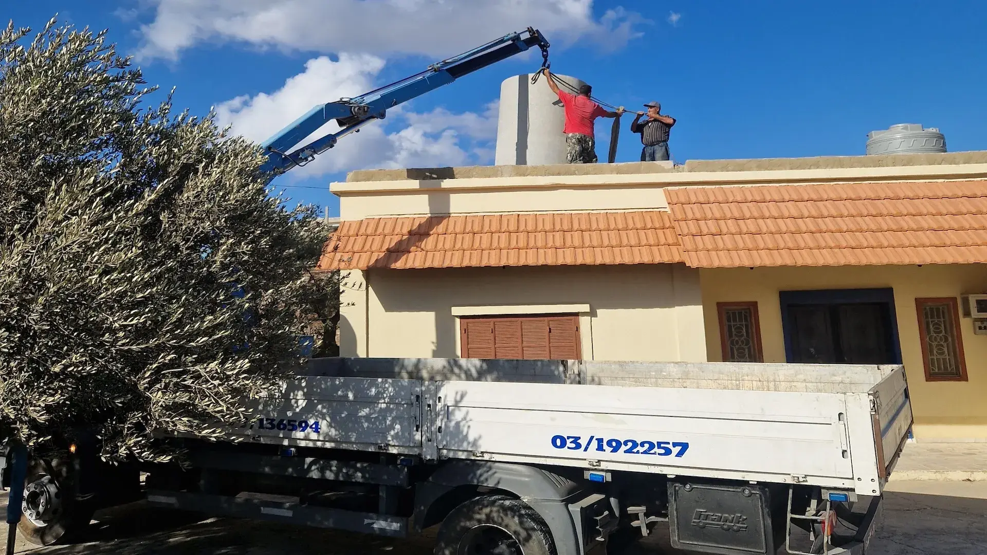 Sayed Transport crane lifting a water tank onto a rooftop in Lebanon